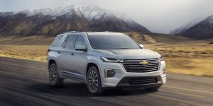 2022 Chevrolet Traverse driving down a highway road with mountains in the background.