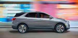 A 2023 Chevrolet Equinox driving quickly past blurred city lights.