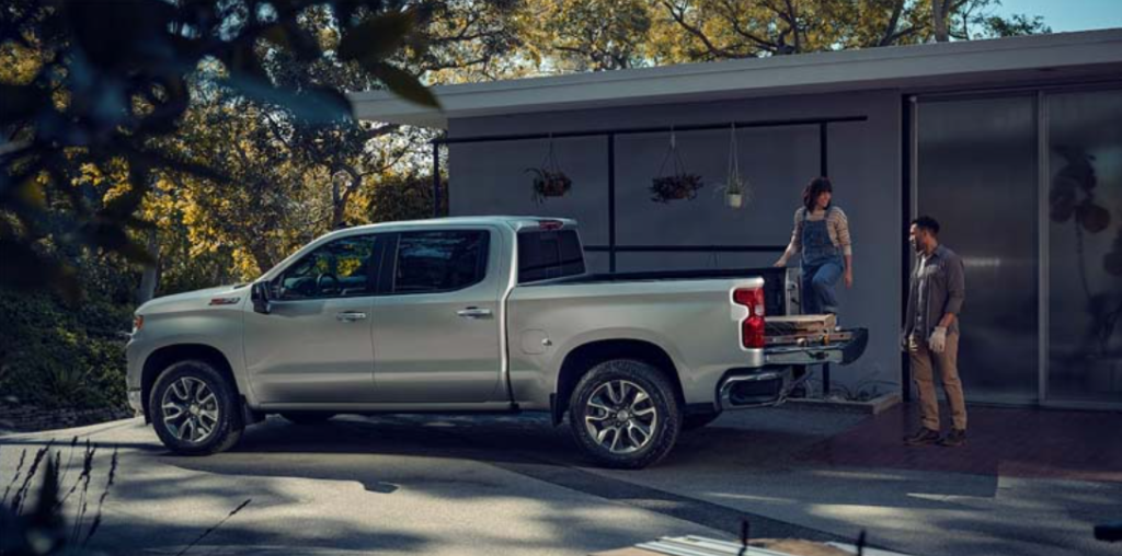 A couple is packing the trunk bed of their silver 2023 Chevrolet Silverado 1500.