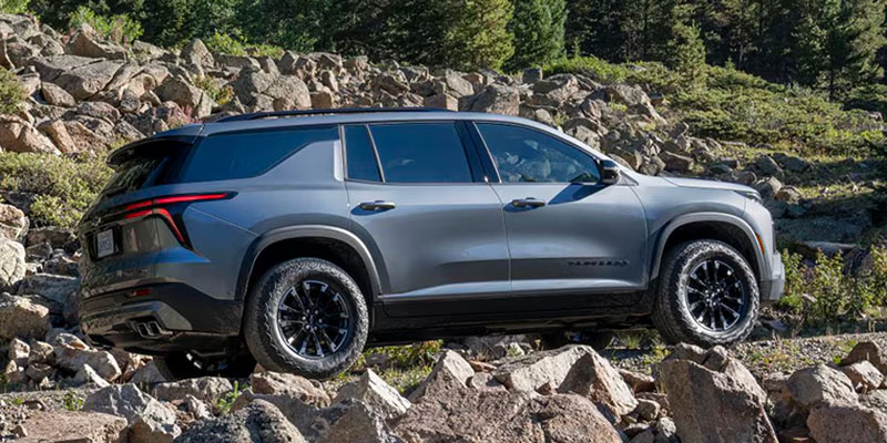 A Chevrolet Traverse SUV navigating through rocky terrain in a mountainous landscape.